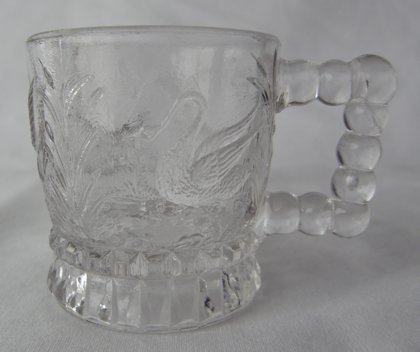 Swan - aka Water Fowl, U.S. Glass No. 3802, or Federal's No. 3802 (Size: 1-7/8" dia. x 2" ht.; Color: Clear) To the left of the handle, sculpting shows a swimming swan among water grasses.